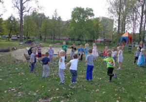 Dzieci ustawione w kole wykonują różne gesty podczas zabawy – podnoszą rękę lub nogę przechylają się w prawo lub lewo.